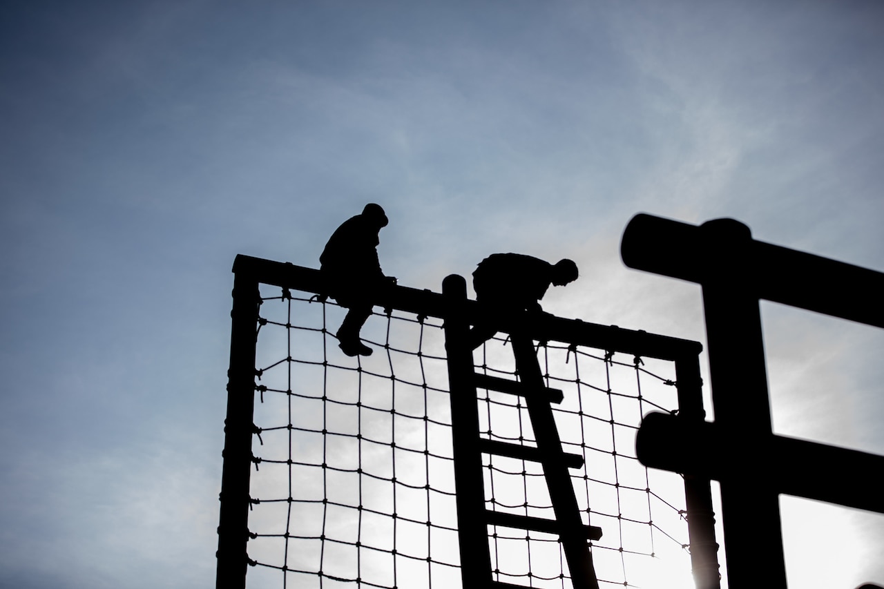 Soldiers in silhouette scale a tall structure.