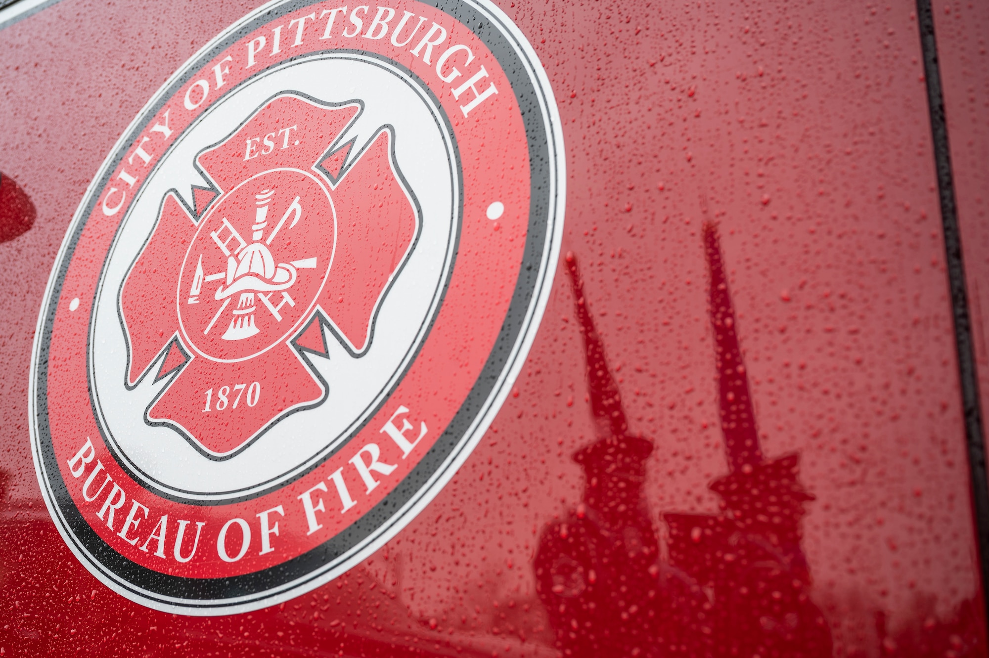 Airmen assigned to the 911th Airlift Wing Honor Guard preparing to present the colors in front of the house of Joseph Wilbon, a World War II veteran, reflect off of a City of Pittsburgh Fire Truck participating in a parade honoring him in Pittsburgh, Pennsylvania, April 11, 2022.