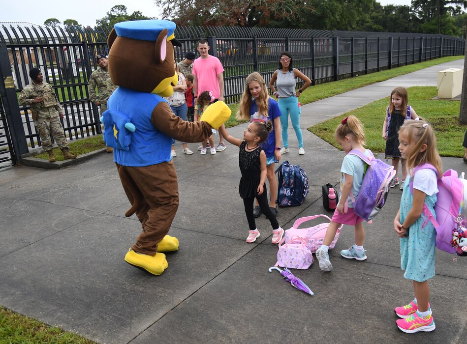 Members of the 81st Security Forces Squadron and Chase the Paw Patrol dog greet military children for the first day of school near the pedestrian gate at Keesler Air Force Base, Mississippi, Aug. 4, 2022. Defenders welcomed the children as they went to Back Bay Elementary School. (U.S. Air Force photo by Kemberly Groue)