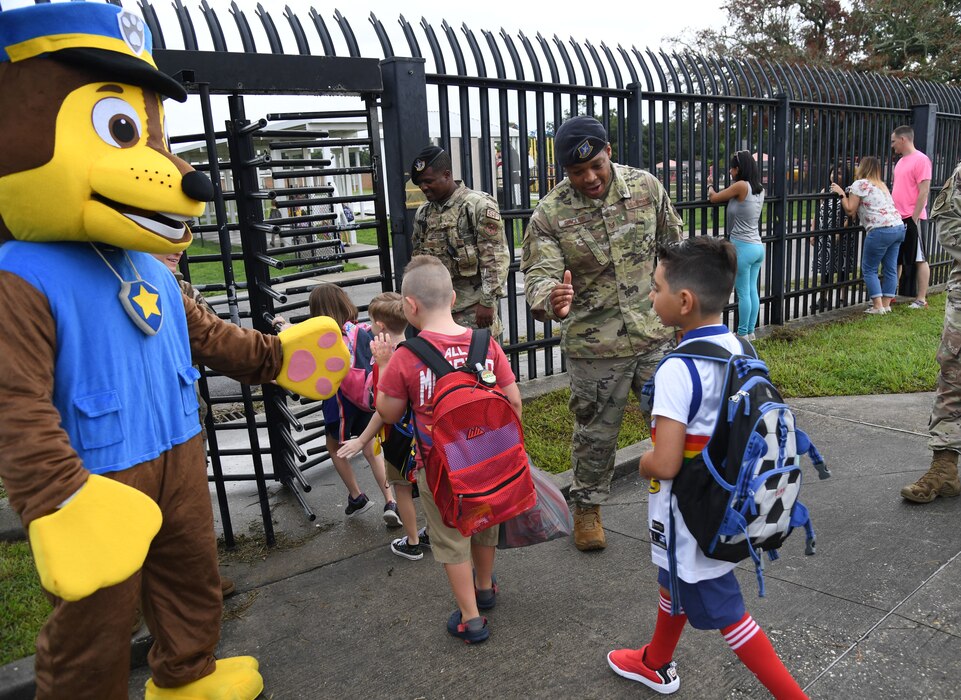 Members of the 81st Security Forces Squadron and Chase the Paw Patrol dog greet military children for the first day of school near the pedestrian gate at Keesler Air Force Base, Mississippi, Aug. 4, 2022. Defenders welcomed the children as they went to Back Bay Elementary School. (U.S. Air Force photo by Kemberly Groue)