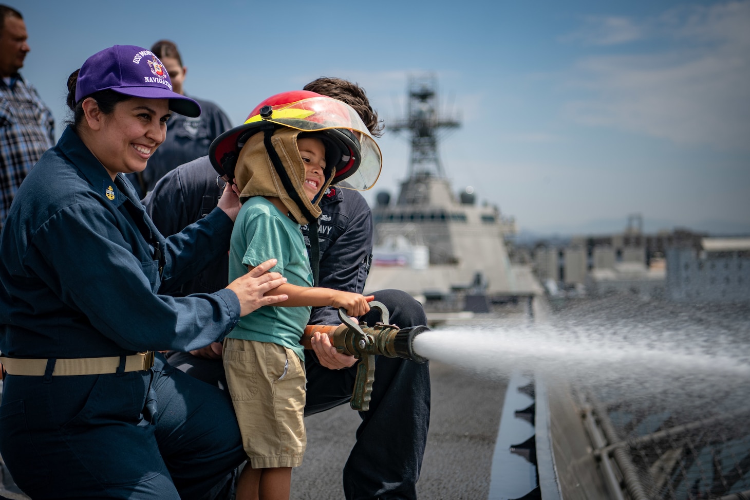 Jayce Bridette, son of Chief Quartermaster Johanna Lopez, controls a fire hose on the flight deck of USS Montgomery (LCS 8) during a "Friends and Family Day."