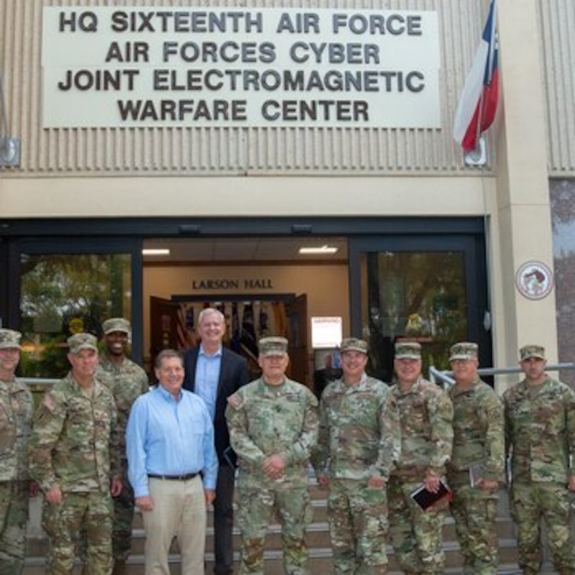 Several military members and civilians pose for a group photo.