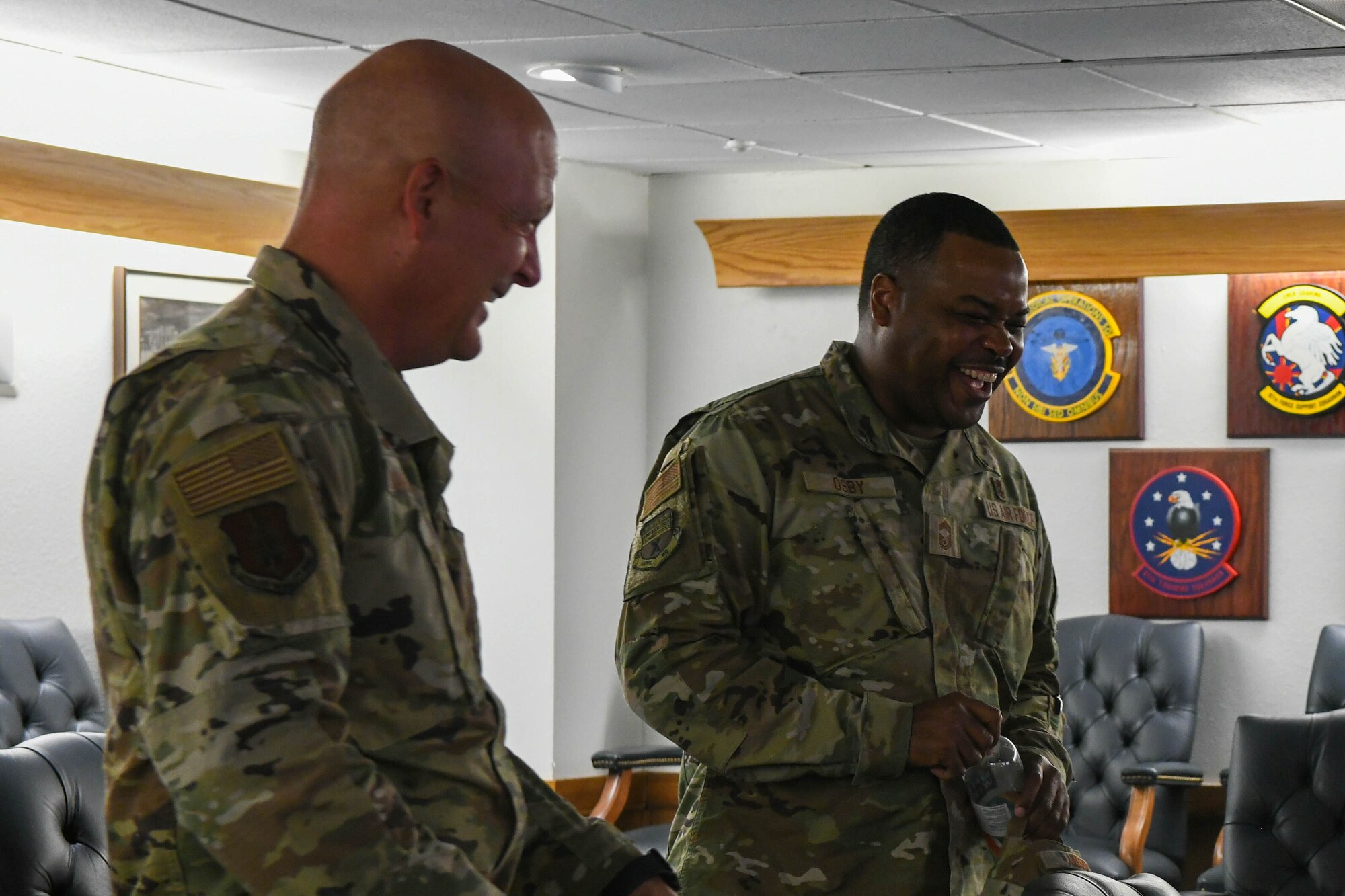 Col. Blaine Baker (left), 97th Air Mobility Wing (AMW) commander, and Chief Master Sgt. Kevin Osby, senior enlisted advisor for the Army and Air Force Exchange Service, laugh together while at Altus Air Force Base, Oklahoma, August 3, 2022. During his visit, Osby was shown the 97th AMW mission brief and had an open discussion with base leaders. (U.S. Air Force photo by Airman 1st Class Trenton Jancze)