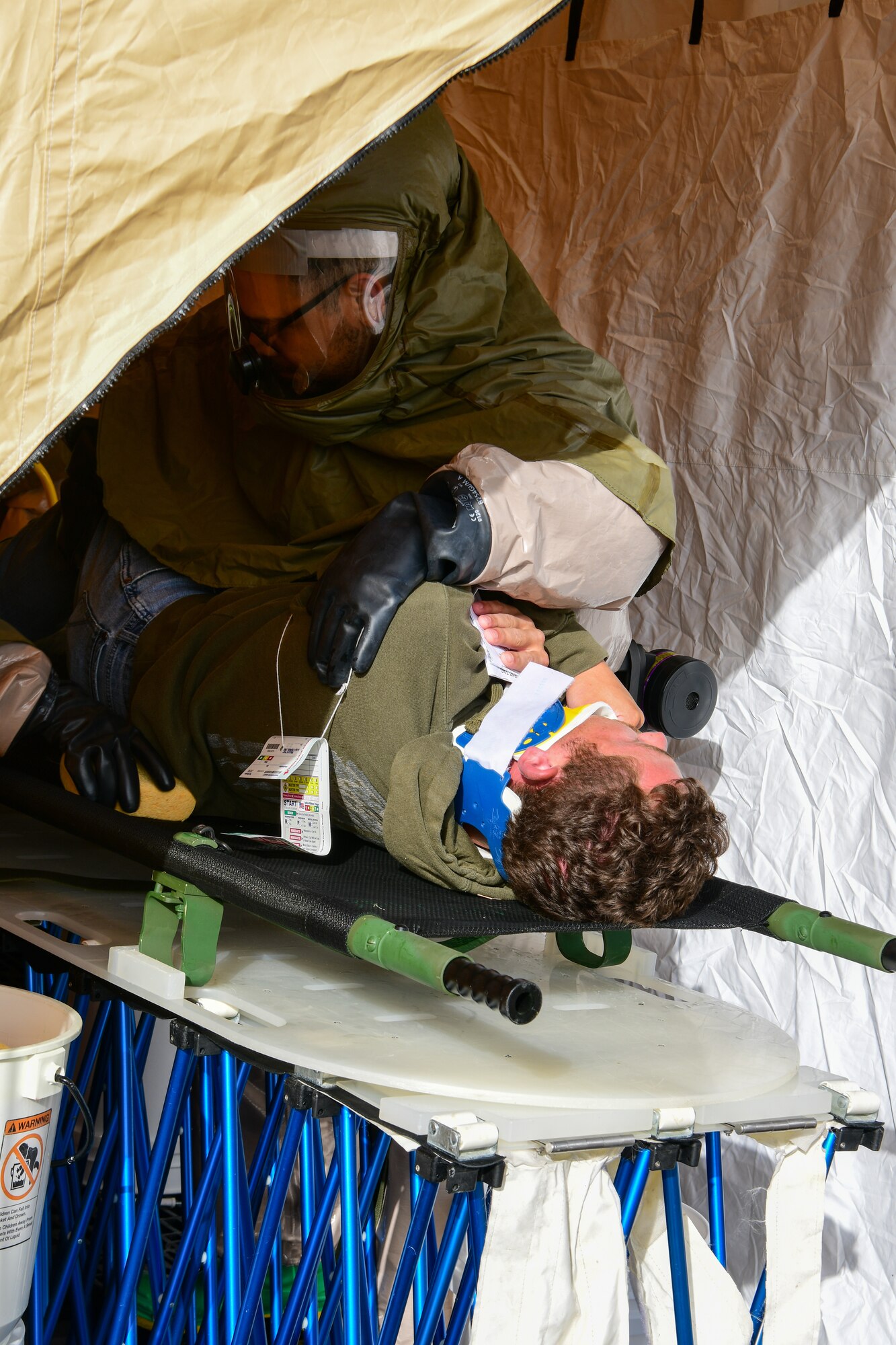 Airmen from the 5th Medical Group wraps a compression bandage around a simulated leg injury during exercise Ready Eagle in the 5th MDG building on Minot Air Force Base Aug. 3, 2022. The exercise allowed Airmen to train and practice Tactical Combat Casualty Care (TCCC), the decontamination process (DCON), and operating in high-tempo situations to prepare them for possible future incidents. (U.S. Air Force photo by Airmen Alysa Knott)