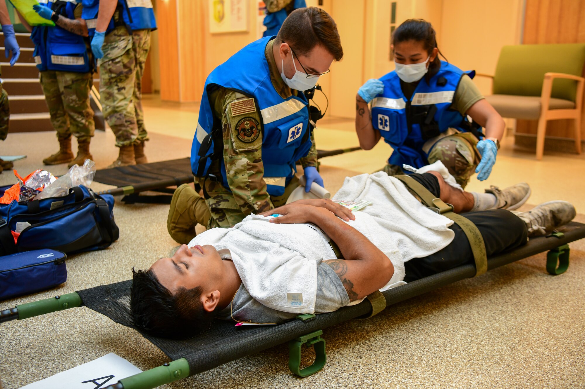 Airmen from the 5th Medical Group wraps a compression bandage around a simulated leg injury during exercise Ready Eagle in the 5th MDG building on Minot Air Force Base Aug. 3, 2022. The exercise allowed Airmen to train and practice Tactical Combat Casualty Care (TCCC), the decontamination process (DCON), and operating in high-tempo situations to prepare them for possible future incidents. (U.S. Air Force photo by Airmen Alysa Knott)