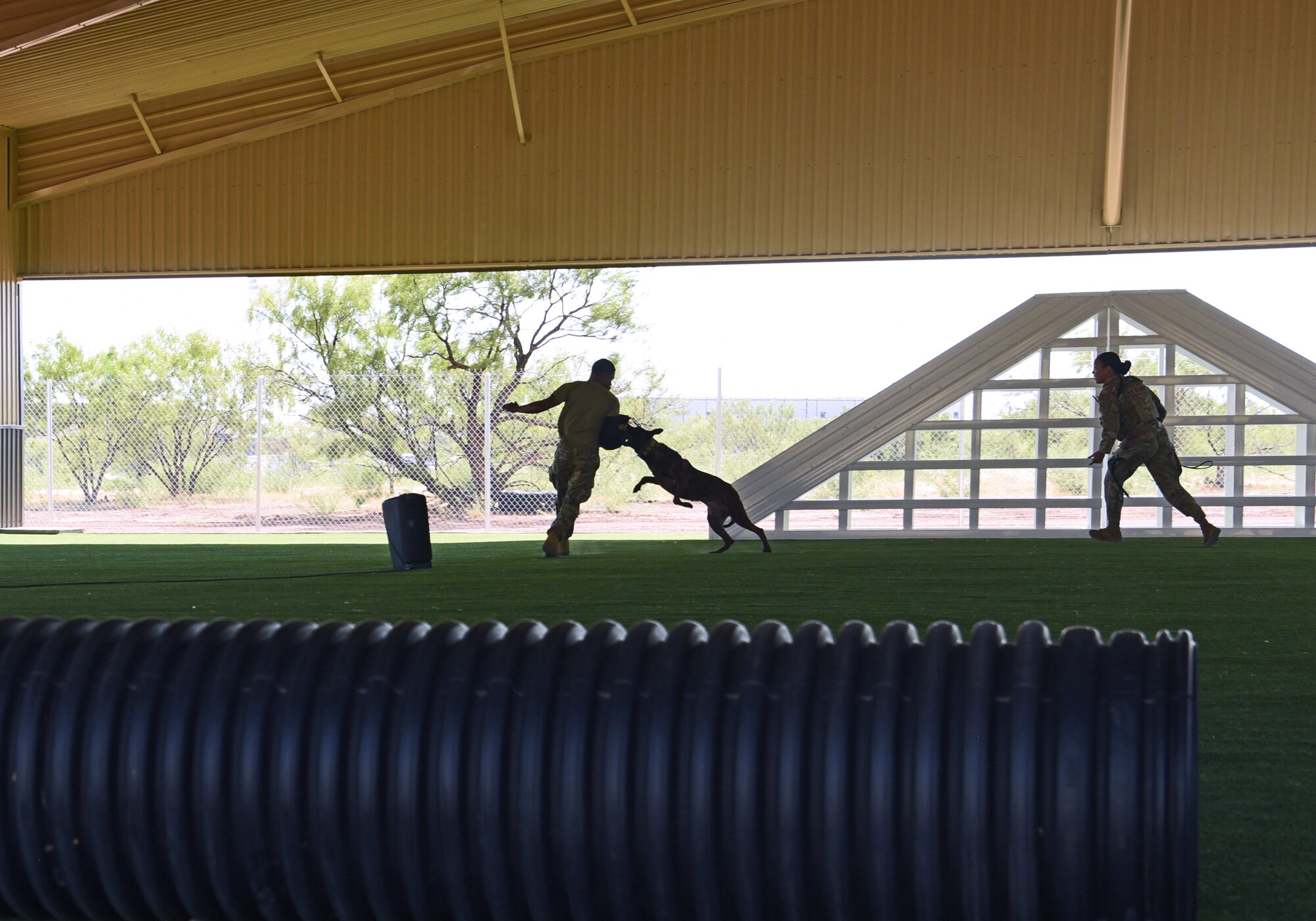 U.S. Air Force Staff Sgt. Damon Hunt, 17th Security Forces Squadron military working dog handler and fellow 17th SFS training partner, is attacked by MWD Aghi, during a capabilities demonstration at Goodfellow Air Force Base, Texas, Aug. 3, 2022. The demonstration was held in a new facility built from a $5.2 million grant secured through the relentless efforts of civic leaders, who have advocated on Goodfellow’s behalf, a testament to the strong and decades long relationship the base has with the local community. (U.S. Air Force photo by Senior Airman Abbey Rieves)