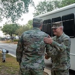 Two leaders in uniform shake hands.