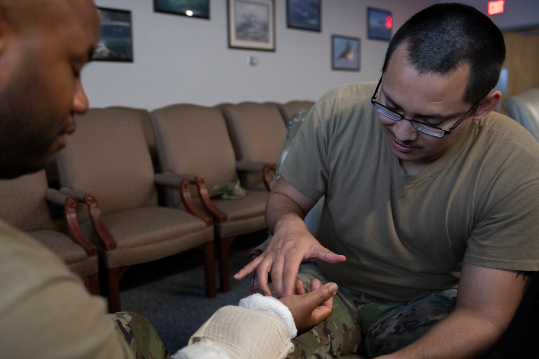 U.S. Air Force Staff Sgt. Alan Garcia, 325th Fighter Wing command post emergency management controller, right, checks that Senior Airman Bertrand Vicks, 325th FW safety technician, has feeling in his hand after applying a pressure bandage at Tyndall Air Force Base, Florida, July 21, 2022. Applying pressure bandages is one of the hands-on skills taught in Tactical Combat Casualty Care, a pre-hospital medical care technique implemented to reduce the number of battlefield deaths. (U.S. Air Force photo by Staff Sgt. Cheyenne Lewis)