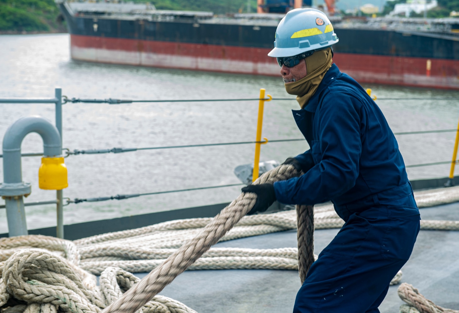 VISAKHAPATNAM, India (Aug. 4, 2022) – Military Sealift Command civil service mariner Benjamin Gatdula, from Guam, assigned to the Emory S. Land-class submarine tender USS Frank Cable (AS 40), heaves in a line as the ship prepares to depart Visakhapatnam, India, Aug. 4, 2022. Frank Cable is currently on patrol conducting expeditionary maintenance and logistics in the 7th Fleet area of operations in support of a free and open Indo-Pacific. (U.S. Navy photo by Mass Communication Specialist 3rd Class Wendy Arauz)