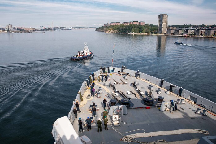 (Aug. 5, 2022)  A Swedish tugboat pulls in front of the San Antonio-class amphibious transport dock ship USS Arlington (LPD 24) during a sea and anchor transit to Stockholm, Sweden, Aug. 5, 2022. The Kearsarge Amphibious Ready Group and 22nd Marine Expeditionary Unit, under the command and control of Task Force 61/2, is on a scheduled deployment in the U.S. Naval Forces Europe area of operations, employed by U.S. Sixth Fleet to defend U.S., allied and partner interests. (U.S. Navy photo by Mass Communication Specialist 1st Class John Bellino)