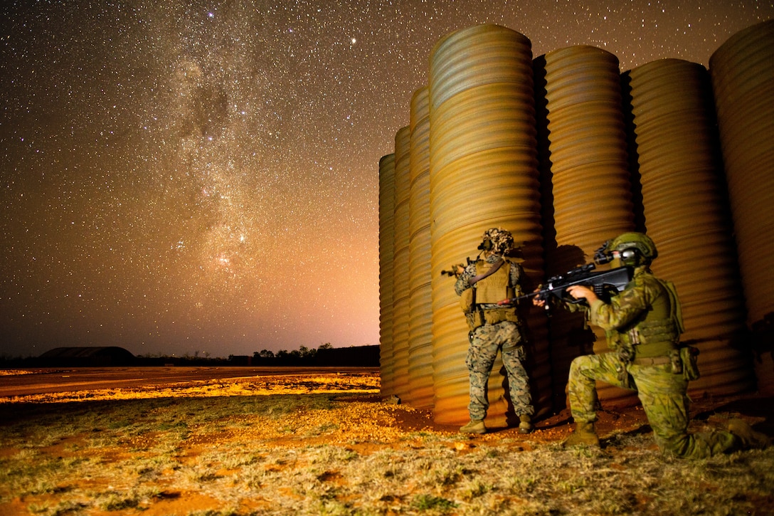 U.S. Marine Corps Lance Cpl. Dexter Madrigal, a rifleman with 3d Battalion, 7th Marine Regiment, Ground Combat Element, Marine Rotational Force-Darwin 22, and Australian Army Pvt. Daniel Rochford, with 16th Battalion, Royal Western Australian Regiment, pose for a photograph under the stars after completing an airfield seizure event as part of exercise Koolendong 22, at Royal Australian Air Force Base Curtin, WA, Australia, July 19, 2022. Exercise Koolendong 22 is a combined and joint force exercise focused on expeditionary advanced base operations conducted by U.S. Marines, U.S. Soldiers, U.S. Airmen, and Australian Defence Force personnel.