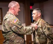 Col. Ron Bonesz, the director of Military Personnel, Illinois Army National Guard, presents Chief Warrant Officer 4 Tim Milligan, of Illiopolis, Illinois, Warrant Officer Strength Manager, Recruiting and Retention Battalion, Illinois Army National Guard, with the Meritorious Service Medal for exceptional work as the personnel actions and officer personnel management branch chief from 2018-2022, during a promotion ceremony Aug. 3 at the Illinois State Military Museum, Springfield, Illinois.