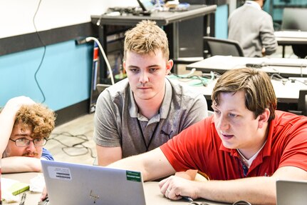 IMAGE: Naval Surface Warfare Center Dahlgren Division Force Analyst Josh Siben (right) assists Warfare Analysis and Digital Modeling Department interns Bradley Wohlfarth (center) and Kyle Gumaer with the Modeling and Simulation Toolbox platform during the Wargaming Hackathon the Innovation Lab on July 12.