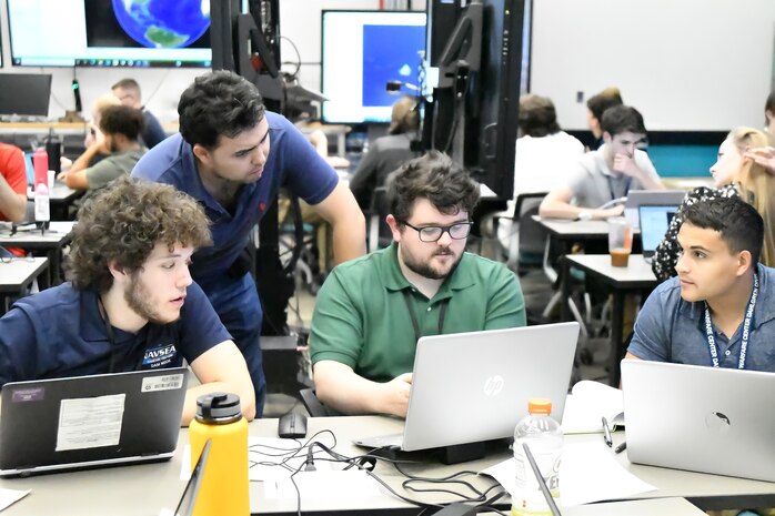 IMAGE: Readiness and Training Systems Department interns (from left to right) Johnathan Gilliam, Alexander Brown, CJ Paterno and Will Anderson collaborate on designing the destroyers that will protect the team’s digital convoy against marauding enemy U-boats during the Wargaming Hackathon at Naval Surface Warfare Center Dahlgren Division’s Innovation Lab on July 12. For some of the summer interns, the competition was the first time they engaged in computer programming and digital modeling activities.