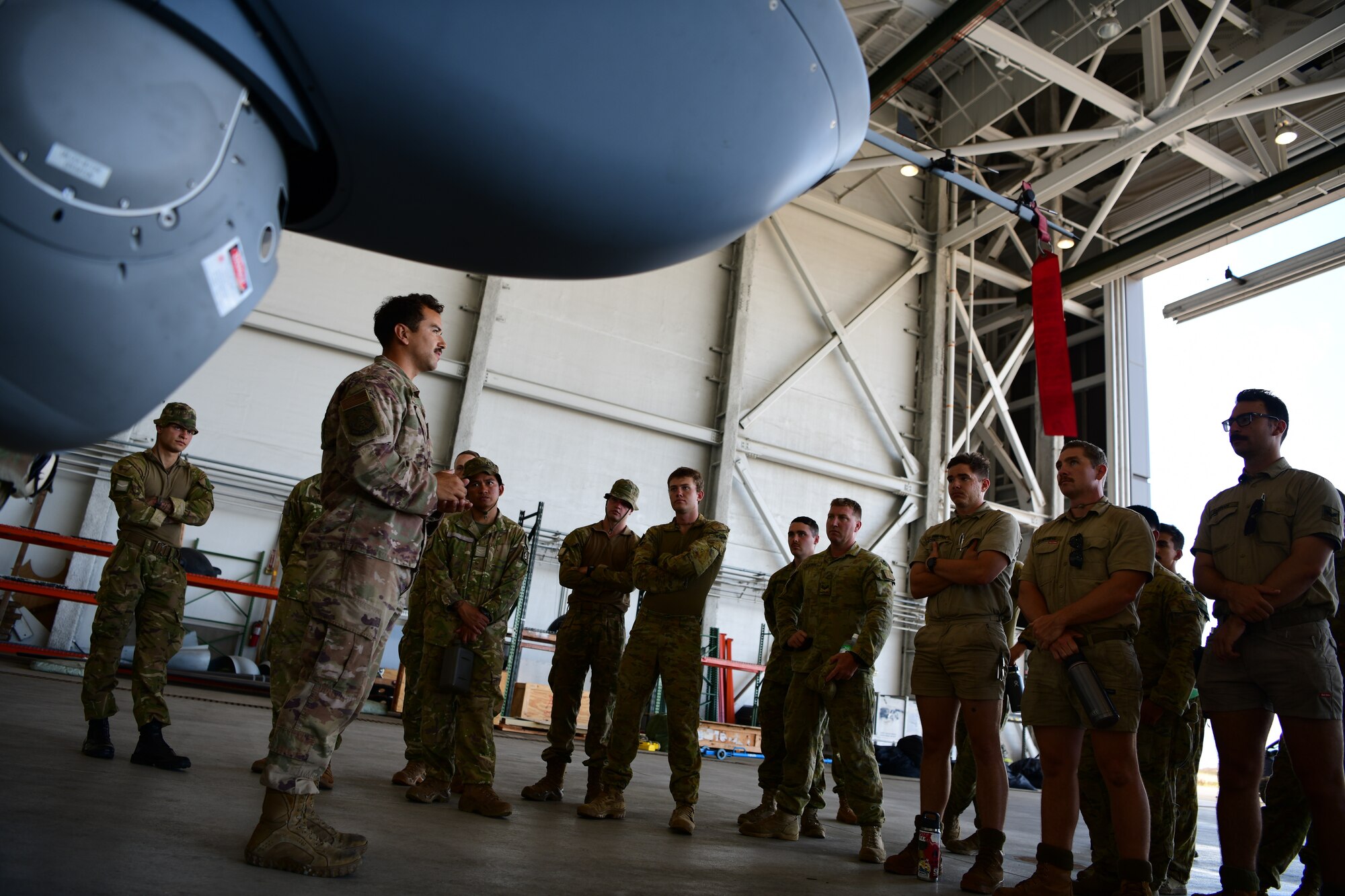 MARINE CORPS AIR STATION KANEOHE BAY, Hawaii (July 28, 2022) U.S. Air Force Staff Sgt. Robert Krupp, 49th Aircraft Maintenance Squadron avionics expeditor technician, explains the MQ-9 Reaper’s mission capabilities to members of the Royal Australian Army and the New Zealand Army during Rim of the Pacific (RIMPAC) 2022, July 28, at Marine Corps Air Station Kaneohe Bay, Hawaii.