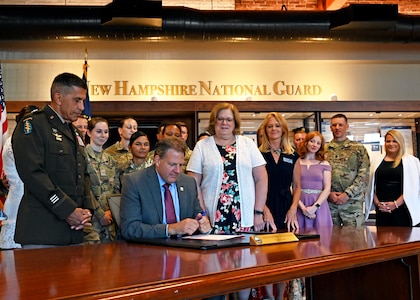 Gov. Chris Sununu signs Senate Bill 360 into law during a small ceremony at state military reservation’s Heritage Room in Concord on Aug. 3, 2022.