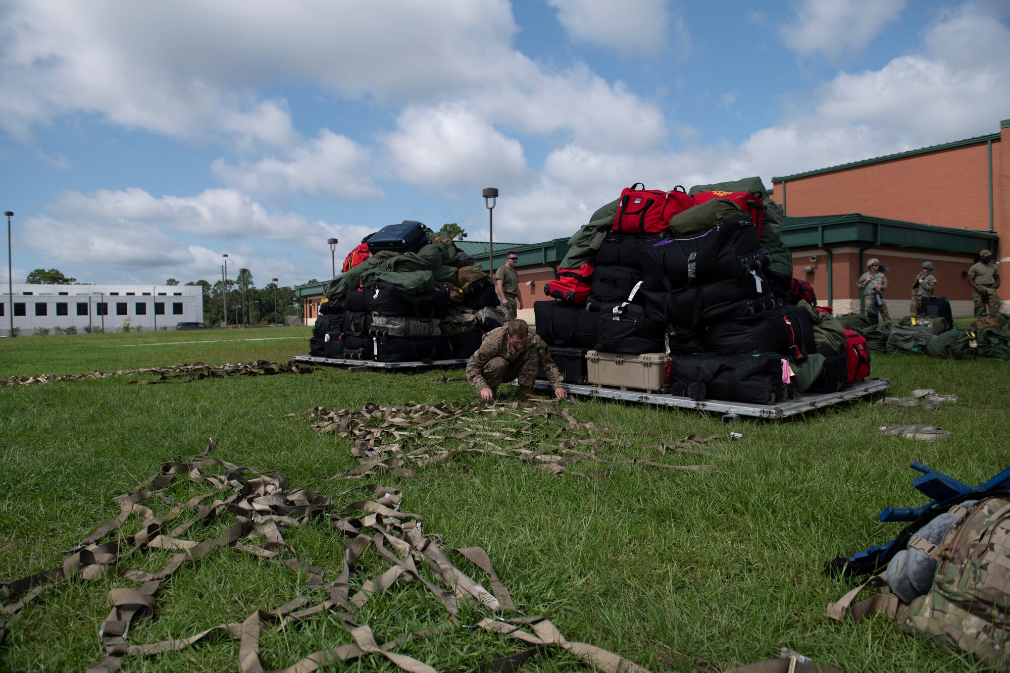 A photo of tie-down straps in the foreground of the photo and in the background there is two pallets of luggage.