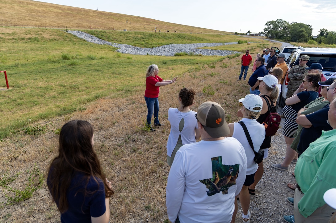 a group of people standing below a dam around cars talking