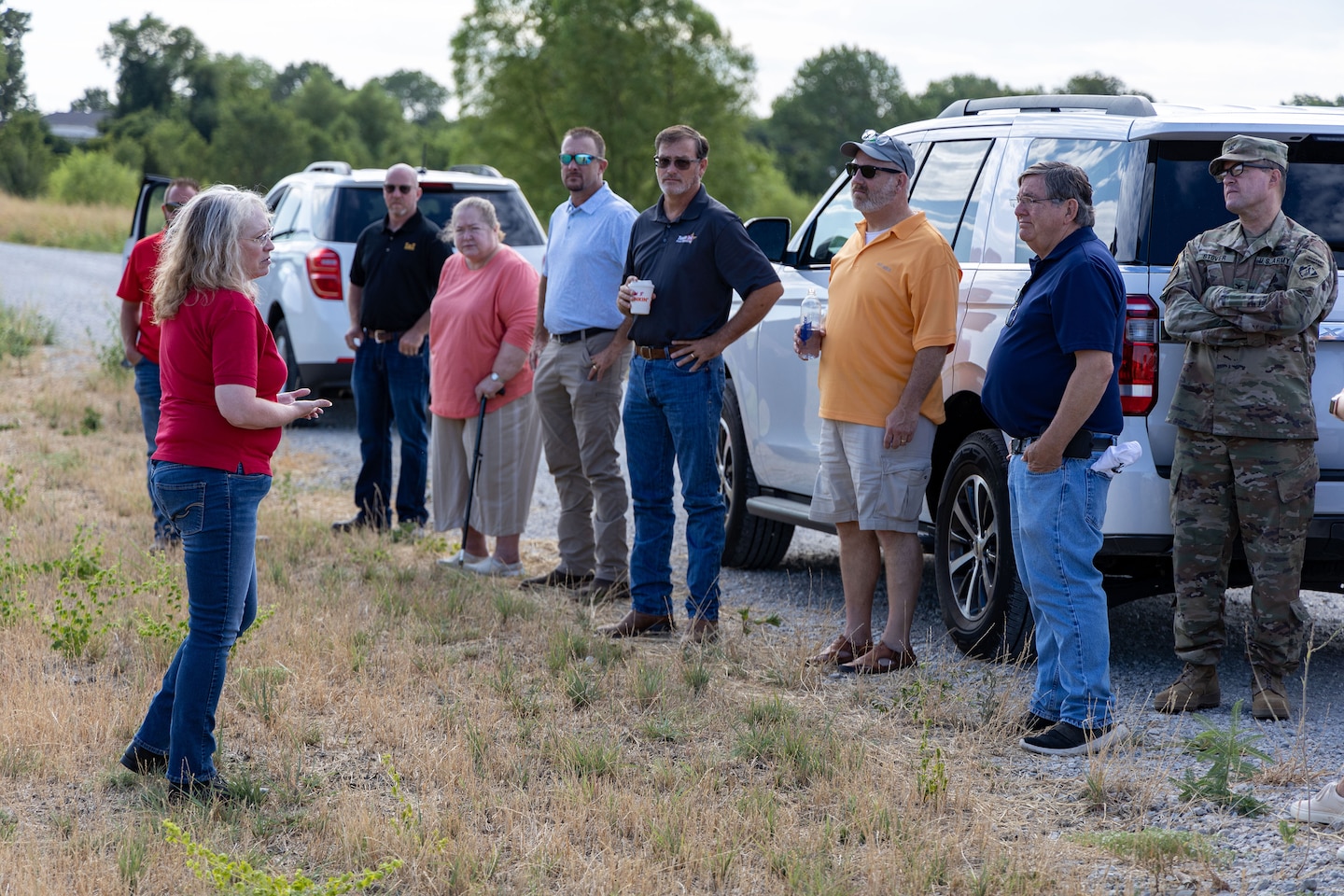 a group of people standing below a dam around cars talking
