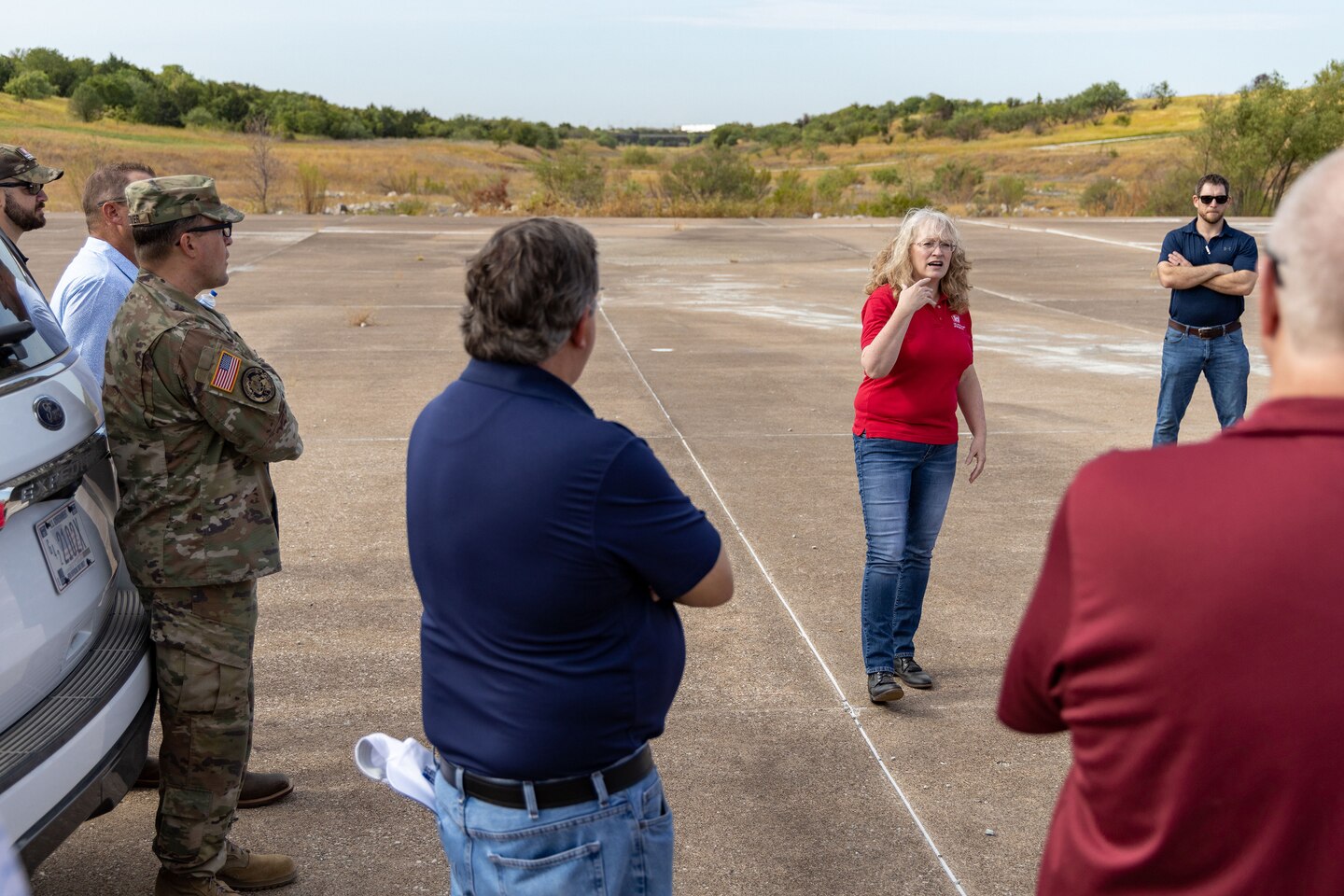 a group of people standing on a dam spillway around cars talking