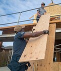 Quartermaster 3rd Class Mitchell Julien hands a wood panel to Lt.j.g. Caitlin Bezecny at a Habitat for Humanity community relations event during Fleet Week Seattle, Aug. 4, 2022.