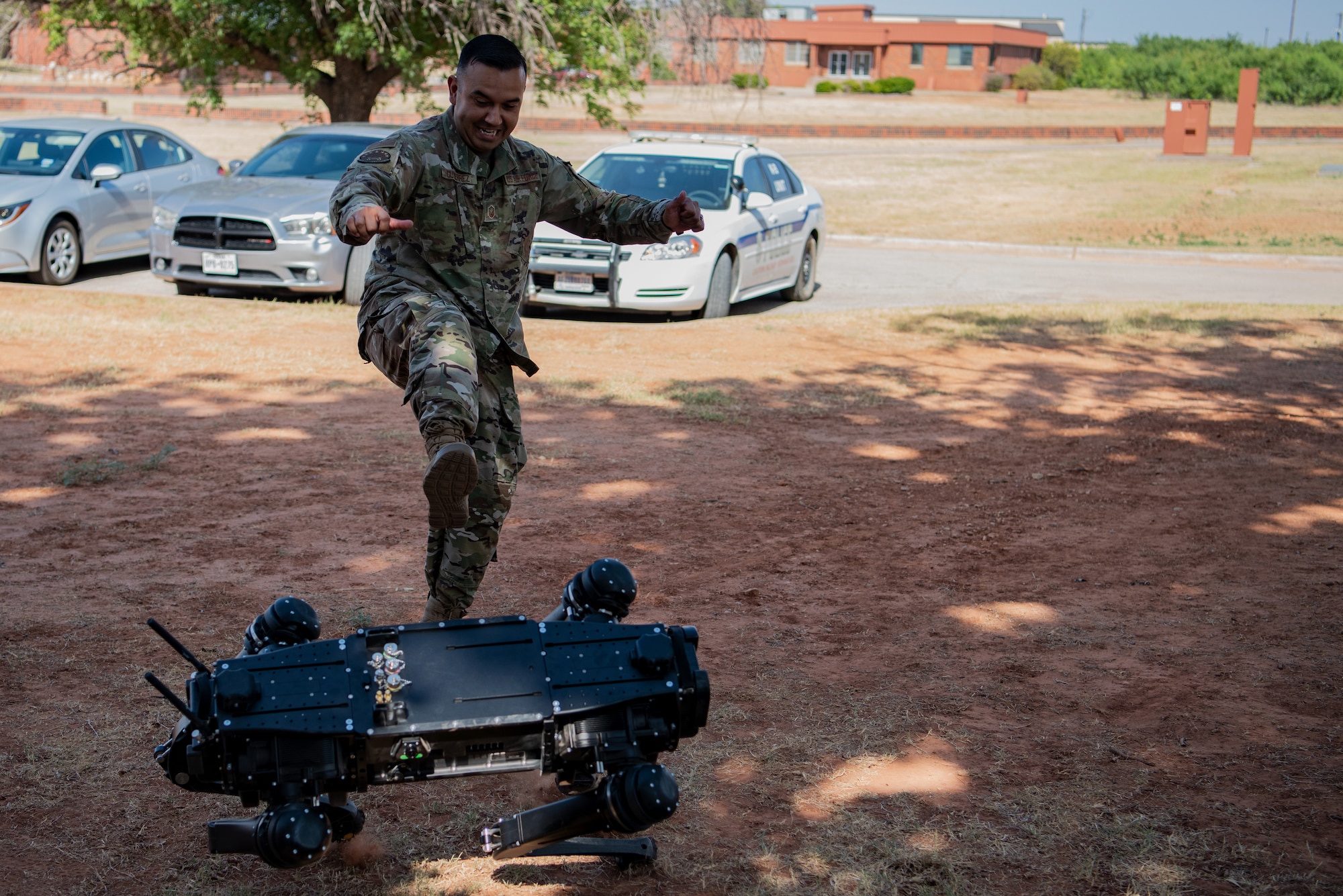 Master Sgt. Jaime Gutierrez, 7th Security Forces Squadron plans and programs superintendent, performs a durability and strength test against a robot dog at Dyess Air Force Base, Texas, Aug. 5, 2022. The addition of the robot dogs will multiply the capabilities of 7th SFS to enable rapid find, fix and finish missions. (U.S. Air Force photo by Airman 1st Class Ryan Hayman)