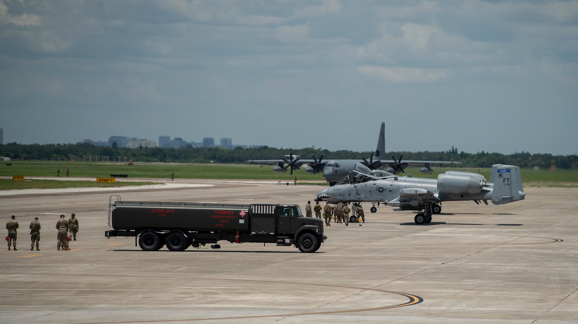 A photo of a fuels truck, two A-10C Thunderbolt II aircraft, and an HC-130J on a flight line.