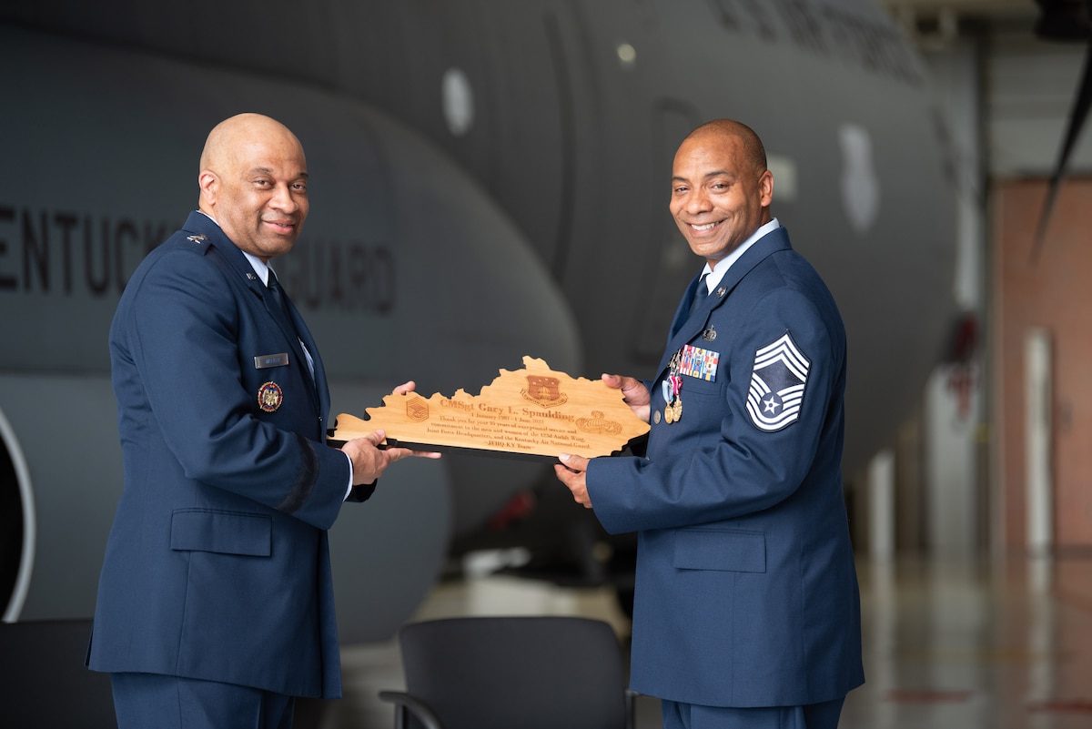 Chief Master Sgt. Gary L. Spaulding, right, military personnel management officer for the Kentucky Air National Guard, receives a plaque from  Maj. Gen. Charles M. Walker, director of the Office of Complex Investigations at the National Guard Bureau, during Spaulding’s retirement ceremony at the Kentucky Air National Guard Base in Louisville, Ky., June 12, 2022. Spaulding served 35 in the Kentucky Air Guard. (U.S. Air National Guard photo by Phil Speck)