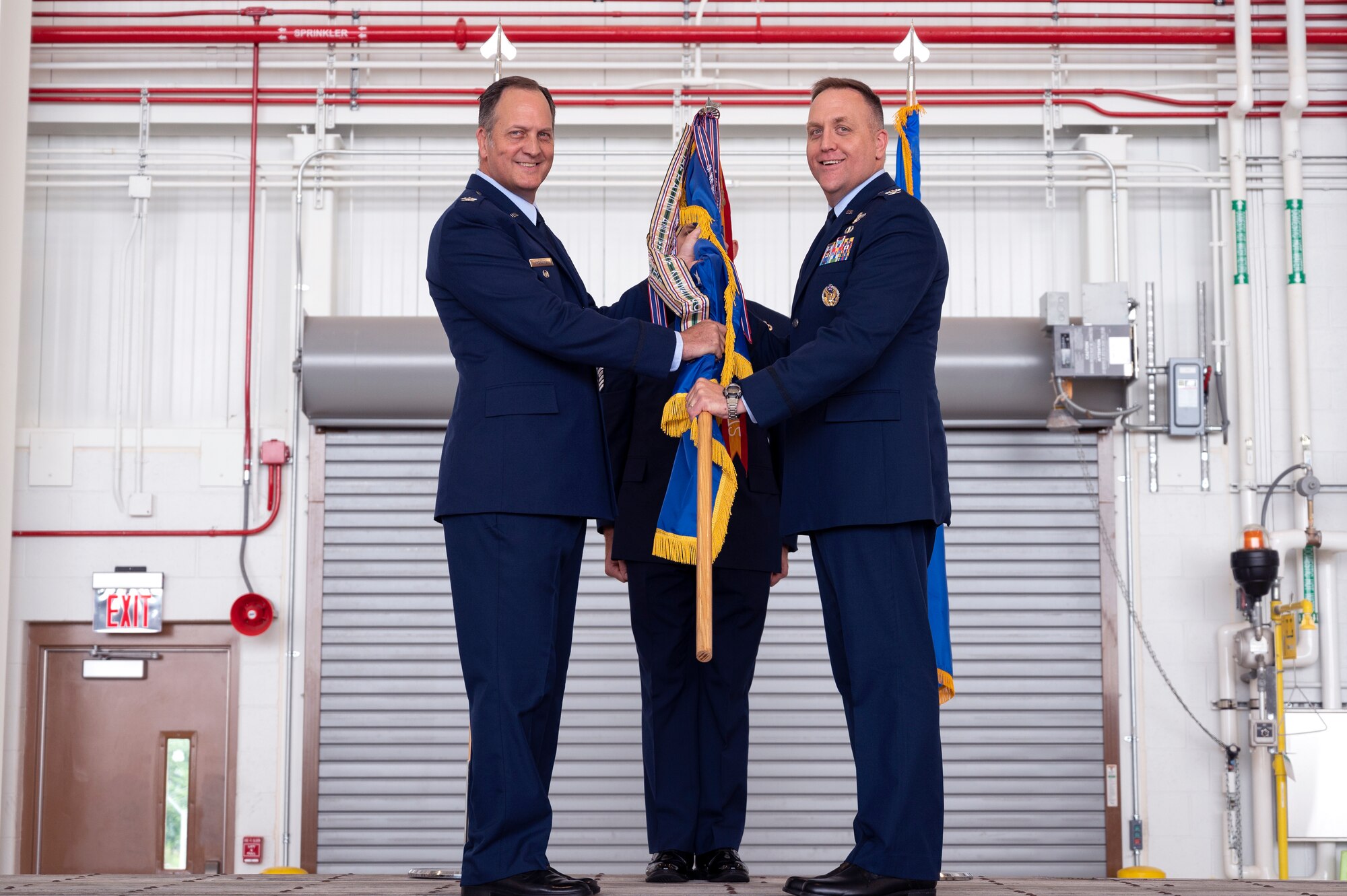 Col. Michael M. Moeding, 4th Air Force vice commander, passes the 911th Airlift Wing guidon to the incoming commander, Col. Bryan M. Bailey, during an assumption of command ceremony at the Pittsburgh International Airport Air Reserve Station, Pennsylvania, Aug. 7, 2022.