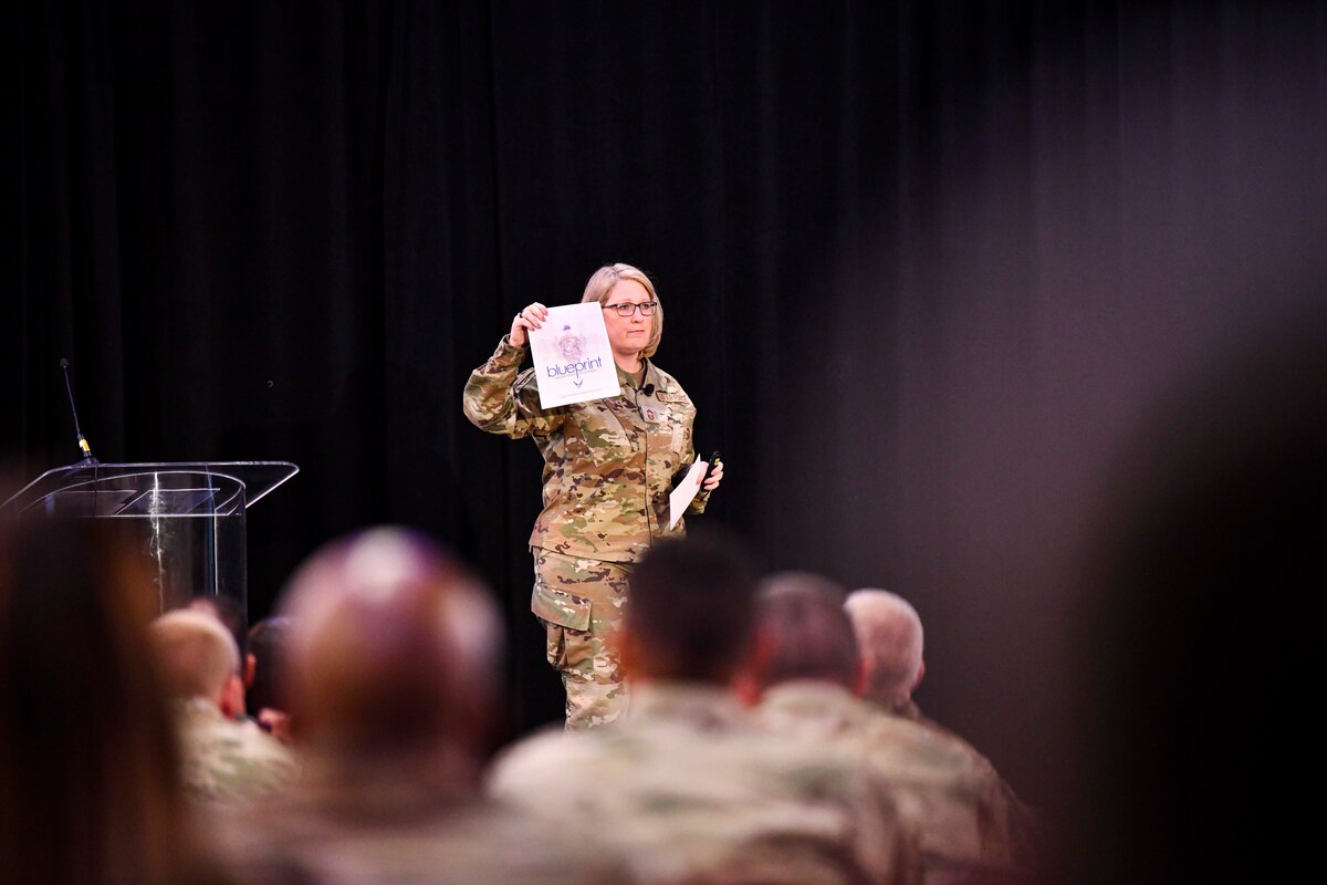 Chief Master Sgt. Megan Parrot, Chief of Enlisted Force Development, holds a copy of The Blueprint: Roadmap to Enlisted Force Development during a speech on enlisted professional developlment at the Enlisted Symposium, July 12, 2022, in Washington, D.C. The symposium was created to provide Reserve Citizen Airmen with information from guest speakers and command leadership with the theme, "Building Tomorrow's Leaders Today: Compete, Deter, Win!"