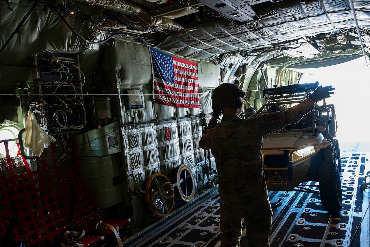 An airman signals to someone loading equipment.