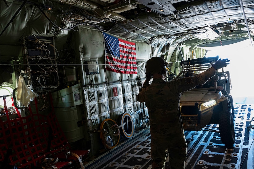 An airman signals to someone loading equipment.