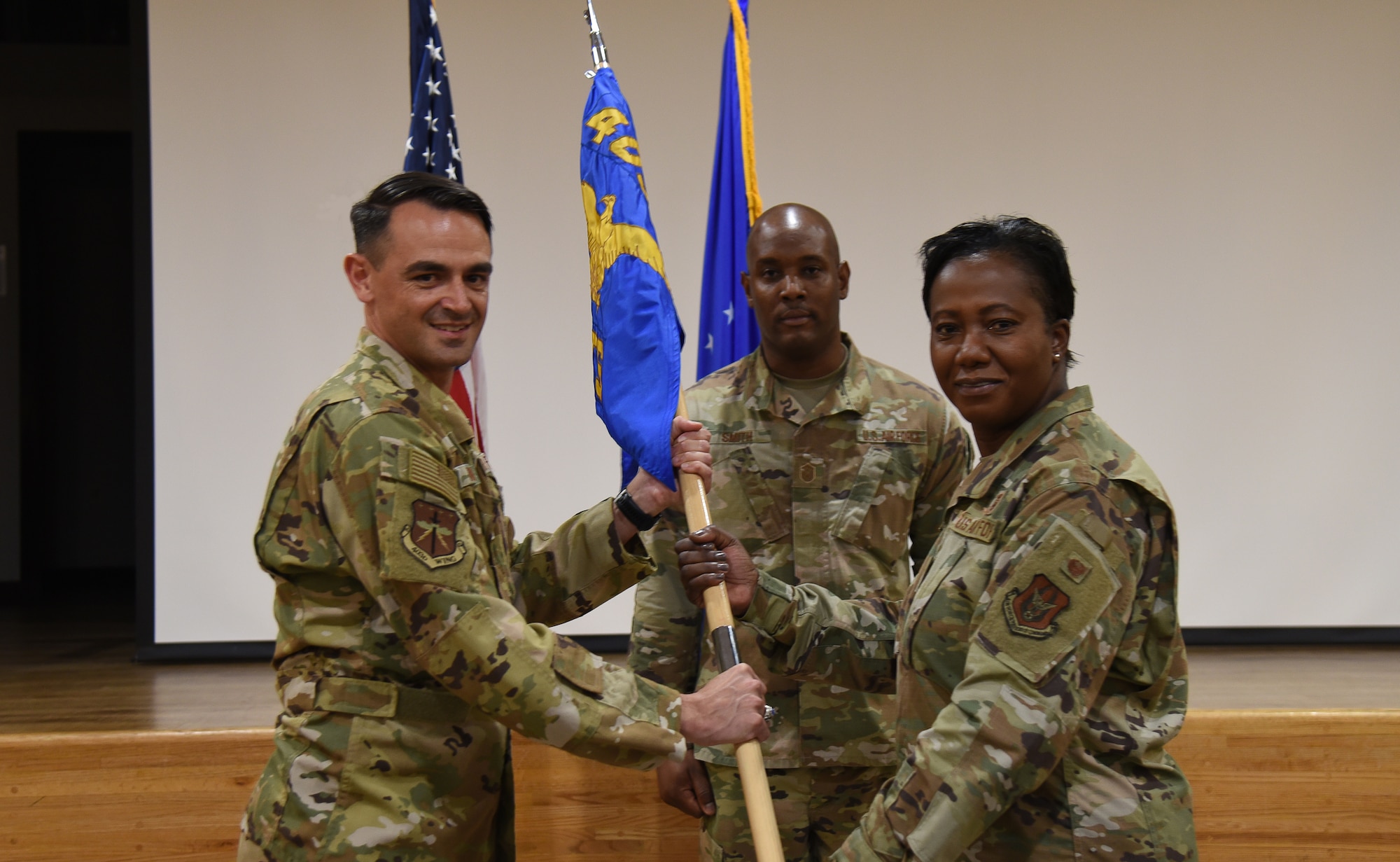Col. Rubio and Col. Collier each hold onto the guidon flag. A third Airman is in the background