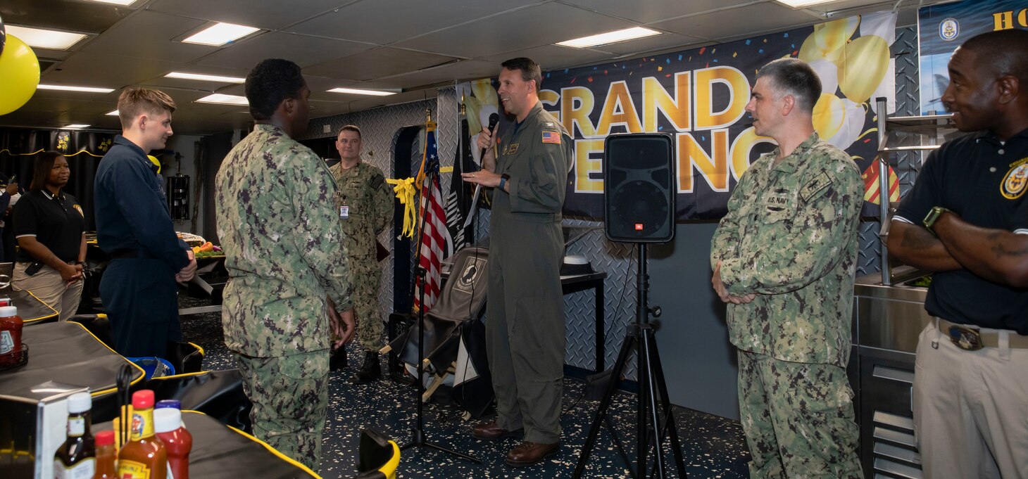 Executive officer gives speech to group of Sailors on the mess decks