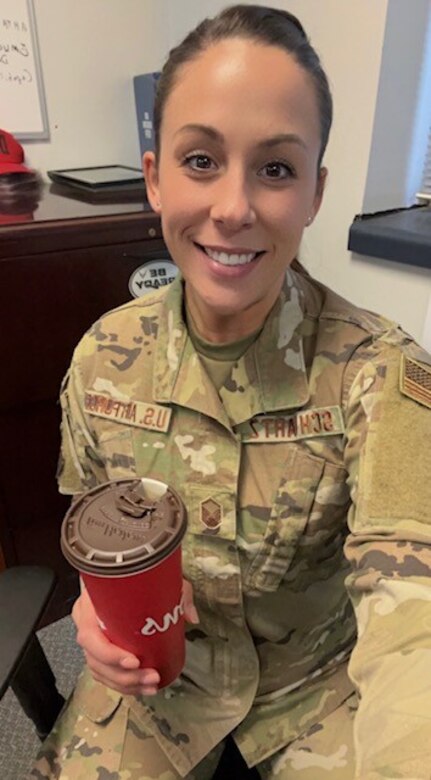 U.S. Air Force Reserve Master Sgt. Amory Schwartz sits smiling with a coffee cup in her hand.