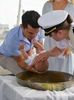 NAVAL STATION NORFOLK (Aug. 5, 2022) Lt. Alisa L. Harl, chaplain aboard the guided-missile destroyer USS Laboon (DDG 58), right, baptizes Blaze Michael Laboon, the great-great-grandnephew of Laboon’s namesake, center. Shipboard bell baptisms are a centuries-old tradition, and several members of the Laboon family have been baptized in the ship’s bell. (U.S. Navy photo by Mass Communication Specialist 1st Class Jacob Milham)