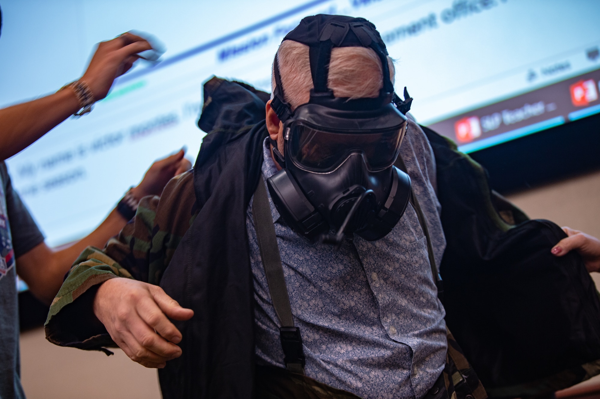 A teacher puts on mission oriented protective posture (MOPP) gear during an immersion tour at MacDill Air Force Base, Florida, Aug 4, 2022. The MOPP demonstration helped teachers better understand the safety precautions military parents experience when they deploy. (U.S. Air Force photo by Airman 1st Class Michael Killian)