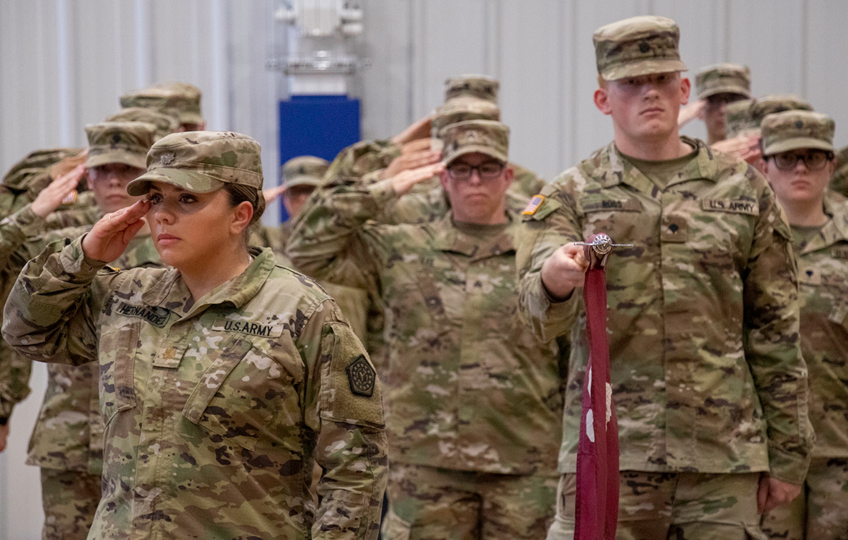 Maj. Karen Hernandez, of Bensenville, Commander of the 709th Medical Company Area Support, based in Bartonville, guidon bearer Spc. Gregg Ross, of Mahomet, with other Soldiers from the unit, salute the U.S. flag during the National Anthem at the deployment ceremony Aug. 6 at the Monroe Elementary School in Peoria.