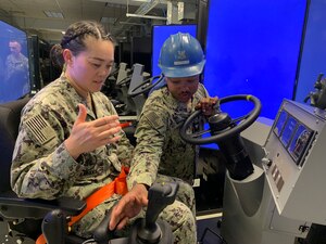 Commander Amy Honek, executive officer for Center for Seabees and Engineering (CSFE), receives directions from Equipment Operator 2nd Class Justin Sobieralski on the proper operation of the “scraper” simulator.