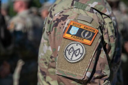 A U.S. Army Soldier assigned to Task Force Orion, 27th Infantry Brigade Combat Team, New York Army National Guard, wears the Combat Training Center-Yavoriv Advisor patch above the 27th IBCT patch during the Joint Multinational Training Group-Ukraine Transfer of Authority ceremony in Grafenwoehr, Germany, August 8, 2022.