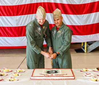 Two officers ceremoniously cutting a cake with a sword