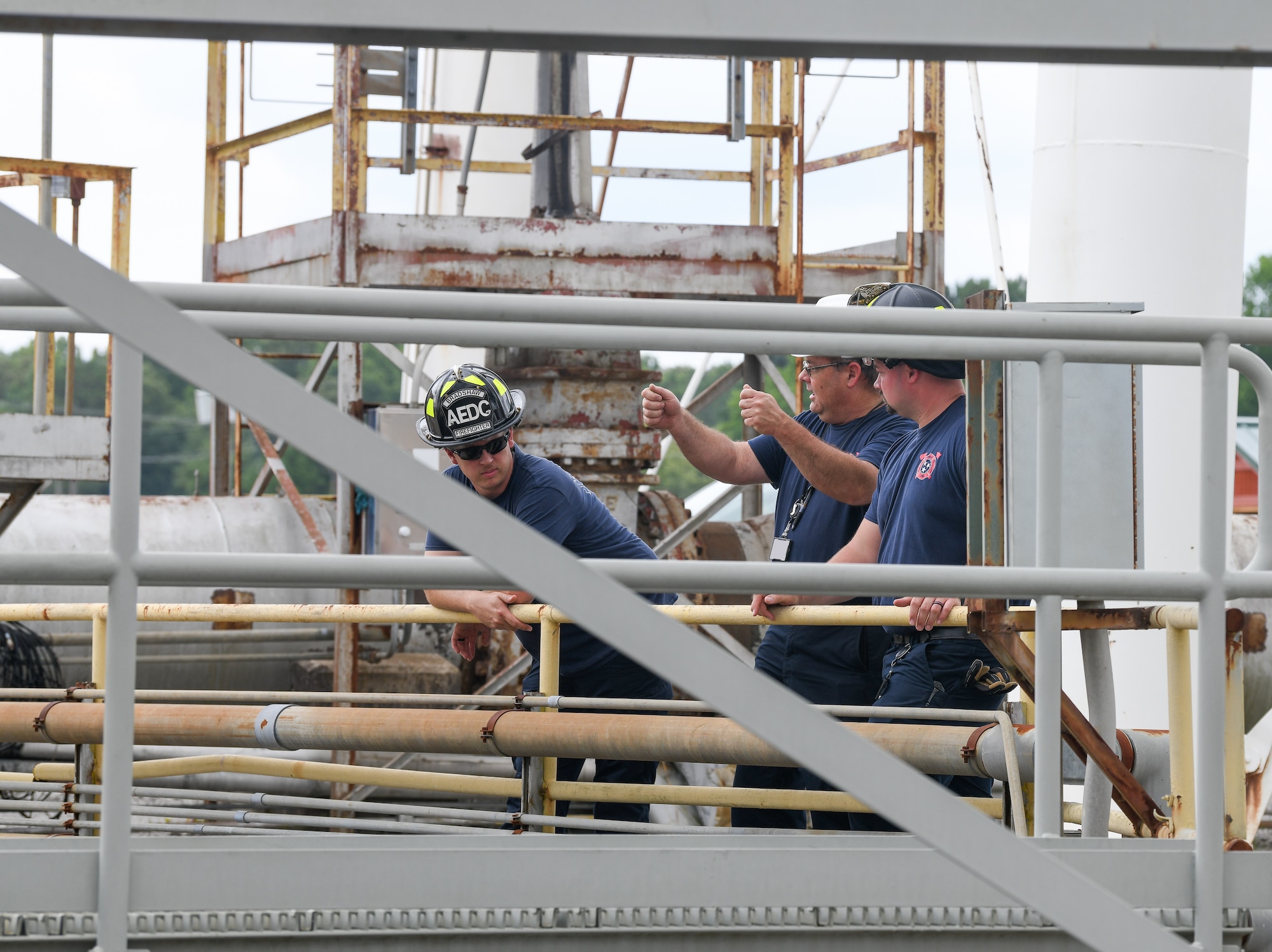 Three firefighters standing next to railing