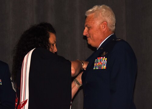 a woman pins an insignia on a man