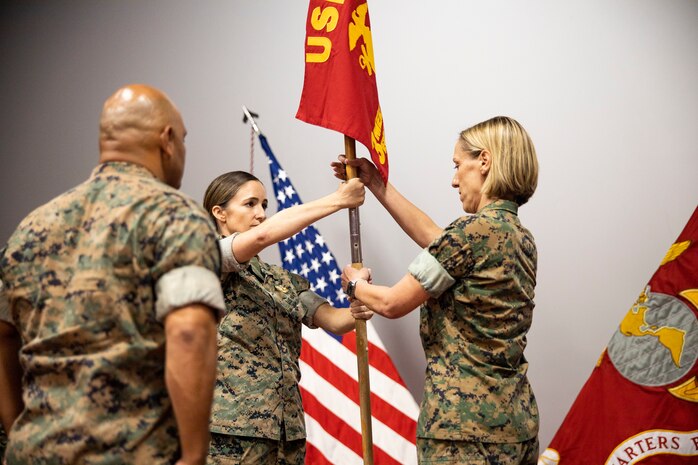 U.S. Navy Cmdr. Autumn Riddell, incoming company commander, receives the company colors from Lt. Cmdr. Jennifer Simmons, outgoing commander, during the Bravo Surgical Company, 3d Medical Battalion change of command, Aug. 1, 2022. Simmons relinquished command to Riddell. (U.S. Marine Corps photo by Cpl. Samantha Sanchez)
