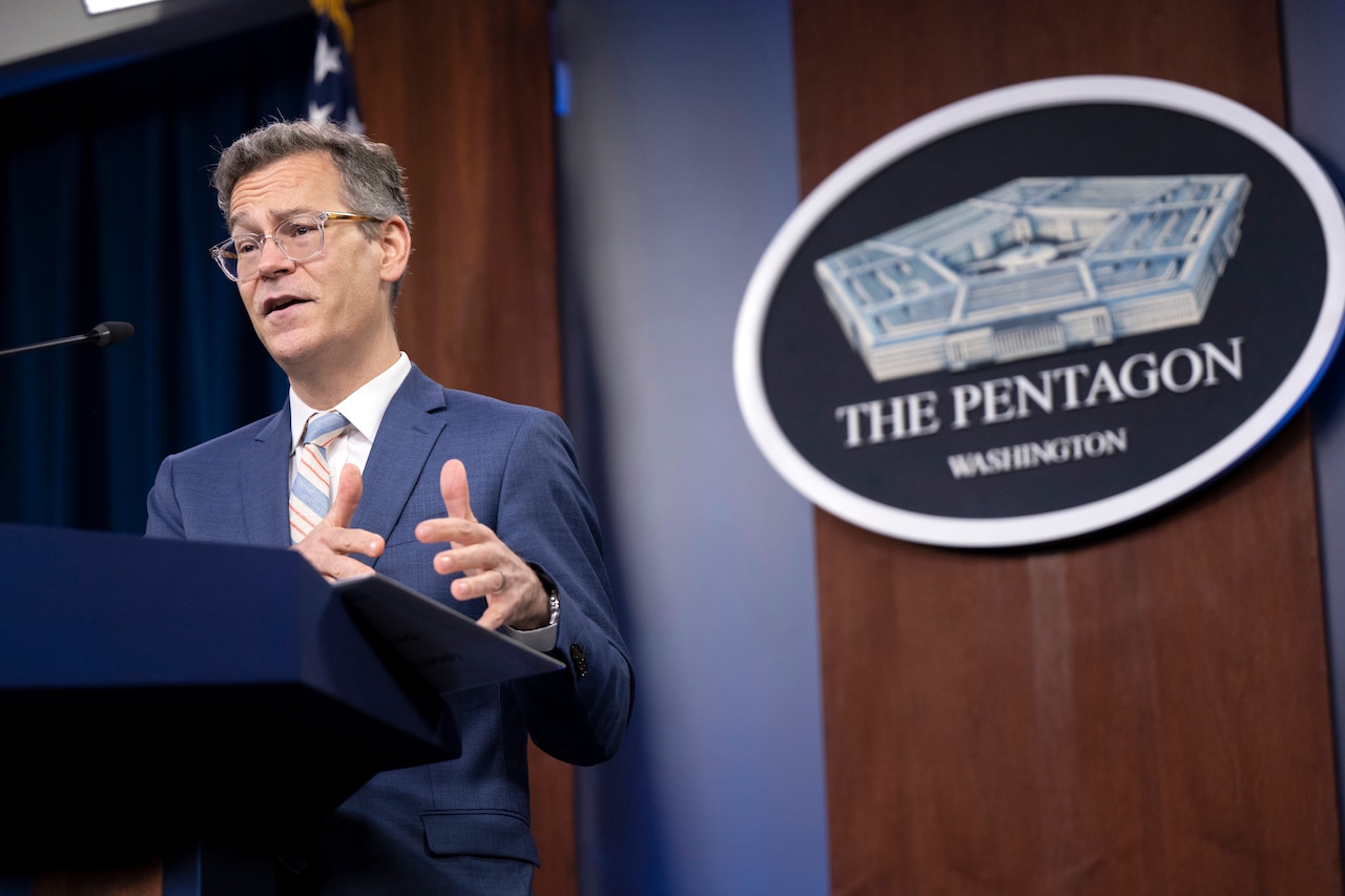 A man stands behind a lectern. The sign behind him indicates that he is at the Pentagon.