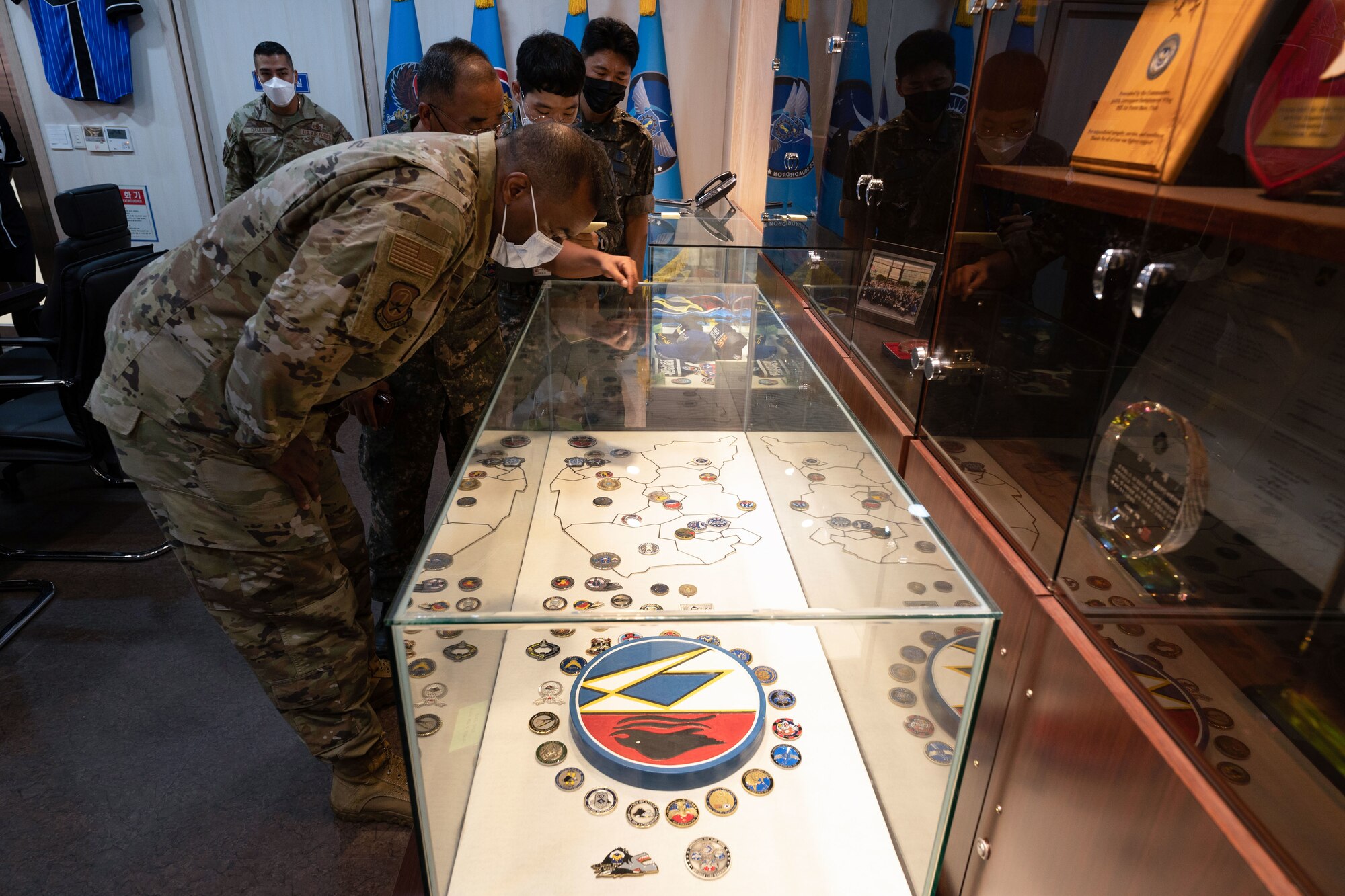 A military member looks into a glass case holding military memorabilia