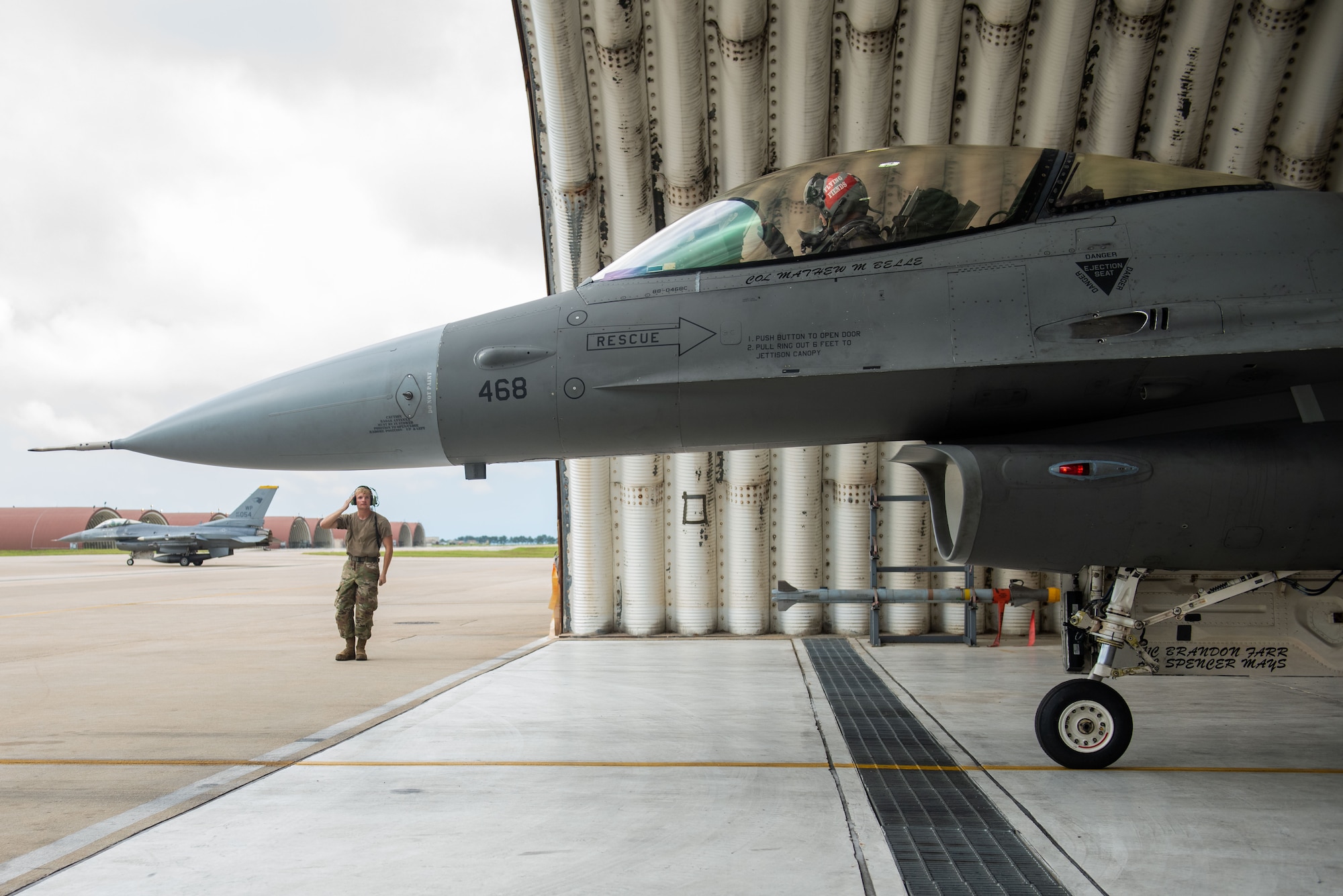 A military member guides a military jet.