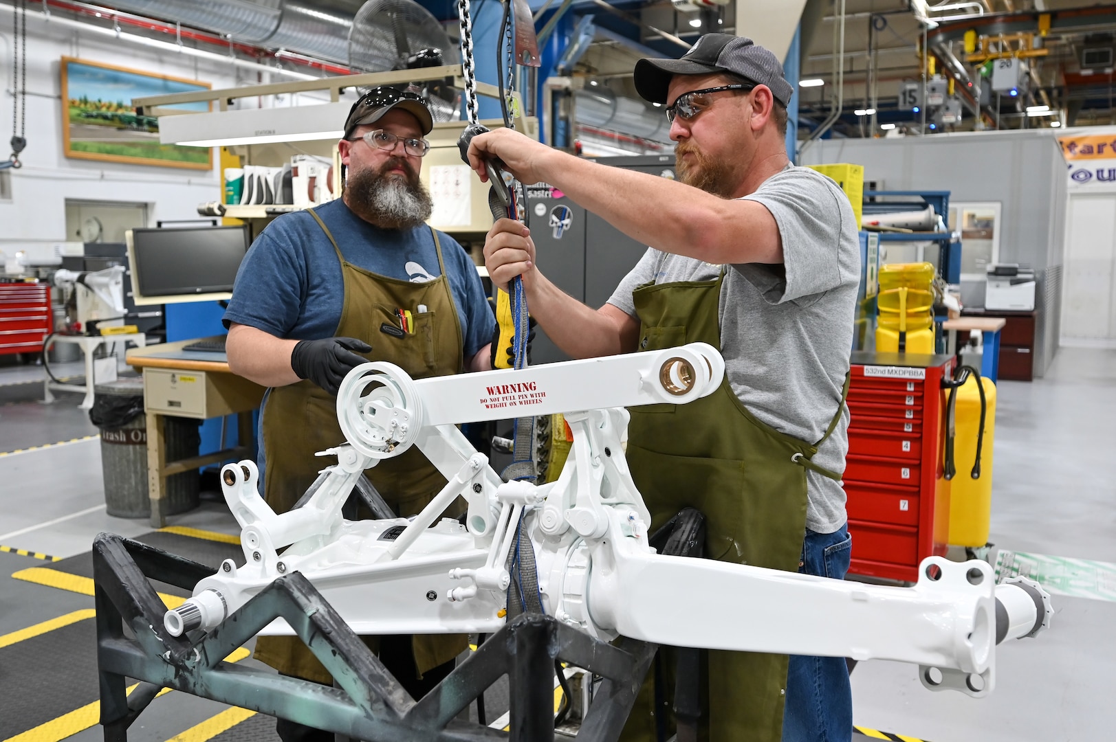 Jim Hamilton and Jeff Harris, 309th Commodities Maintenance Group, attach an F-15 aircraft main landing gear to a hook.