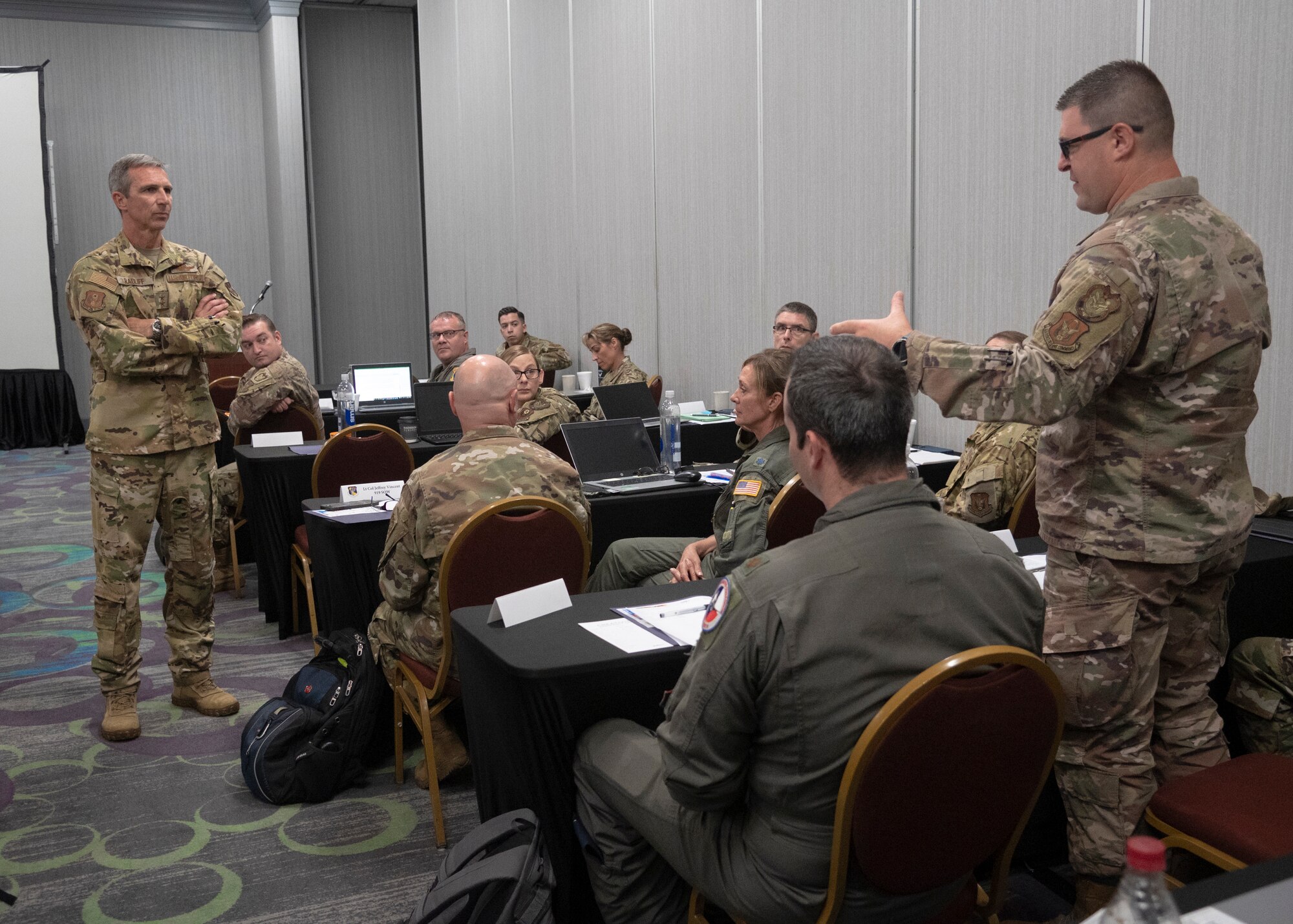 Commander points to paper while addressing 40 people in a room during Inspector General Inspection (IGI) teams across the Numbered Air Force during the first-ever 10th AF IGI conference
