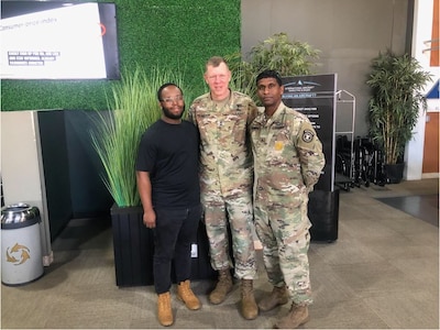 Two Soldiers standing with a civilian.